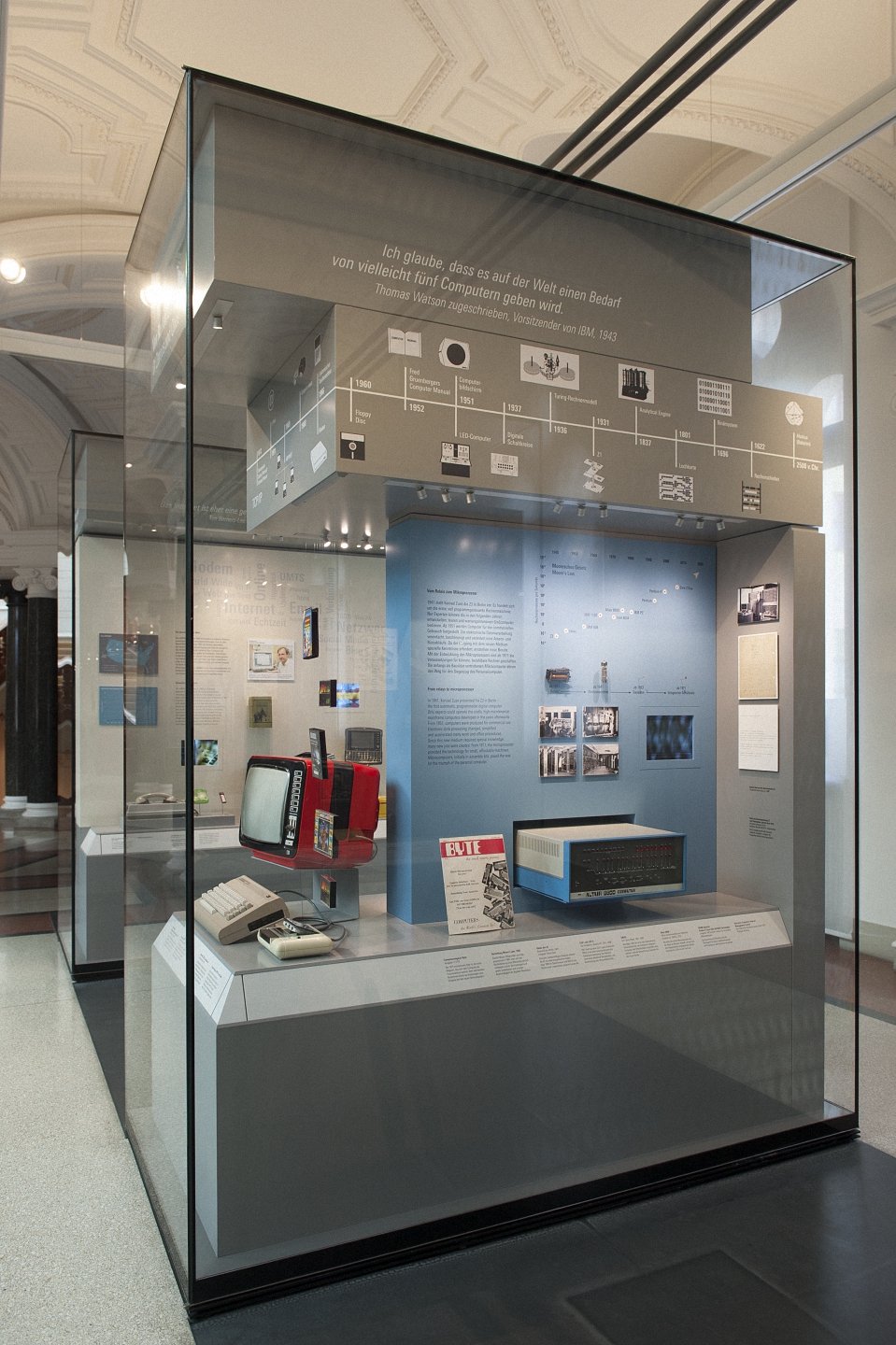 Museumsvitrine mit historischen Computern und Informationsgrafiken zur Entwicklung von Computern im Hintergrund