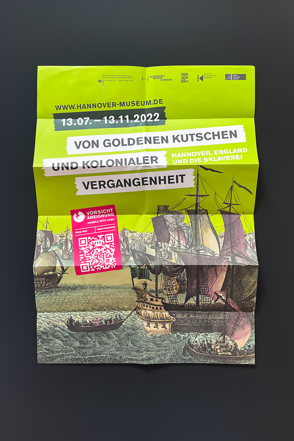 Flyer zur Ausstellung 'Von goldenen Kutschen und kolonialer Vergangenheit' vom 13.07. bis 13.11.2022 im Historischen Museum Hannover. Abgebildet sind historische Segelschiffe auf Wasser.
