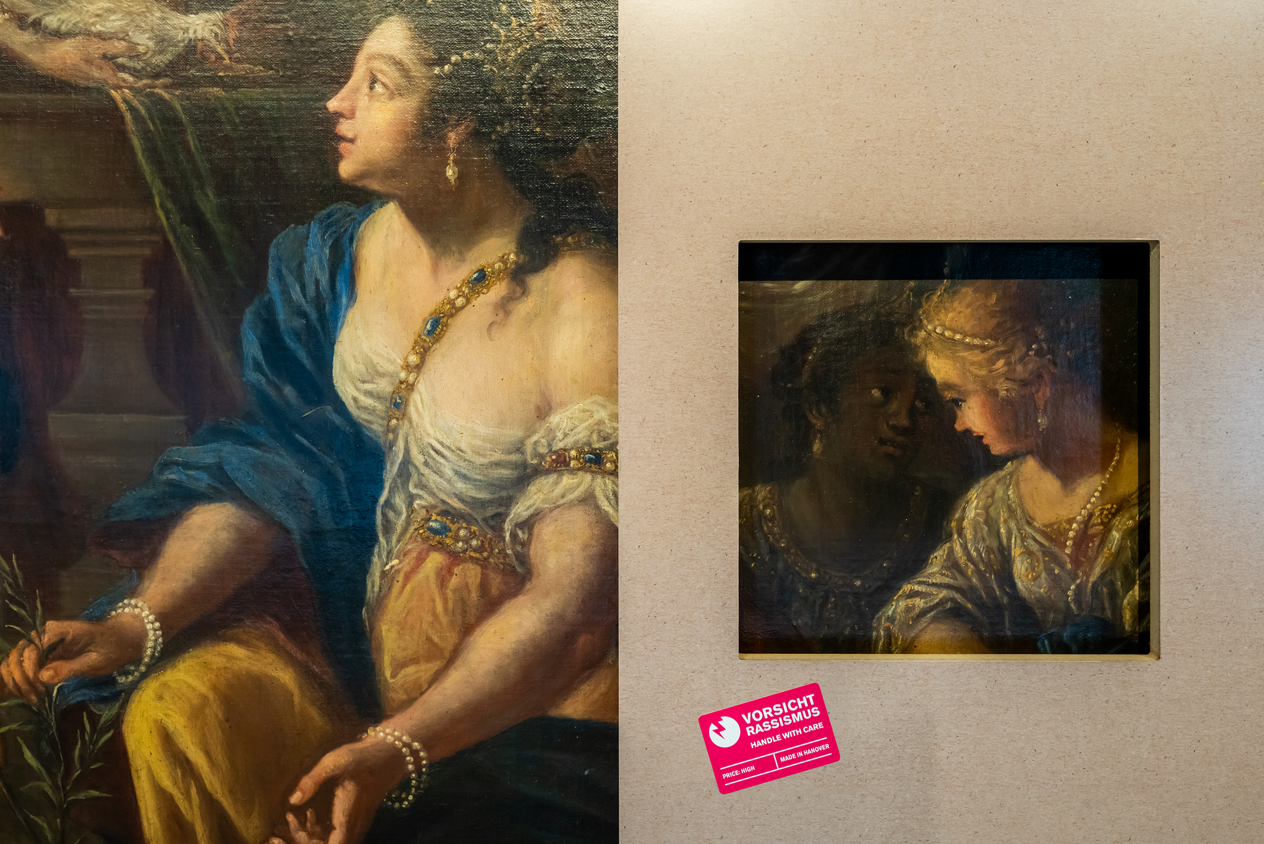 Zwei Gemälde von Frauen, versehen mit einem Aufkleber "Vorsicht Rassismus".