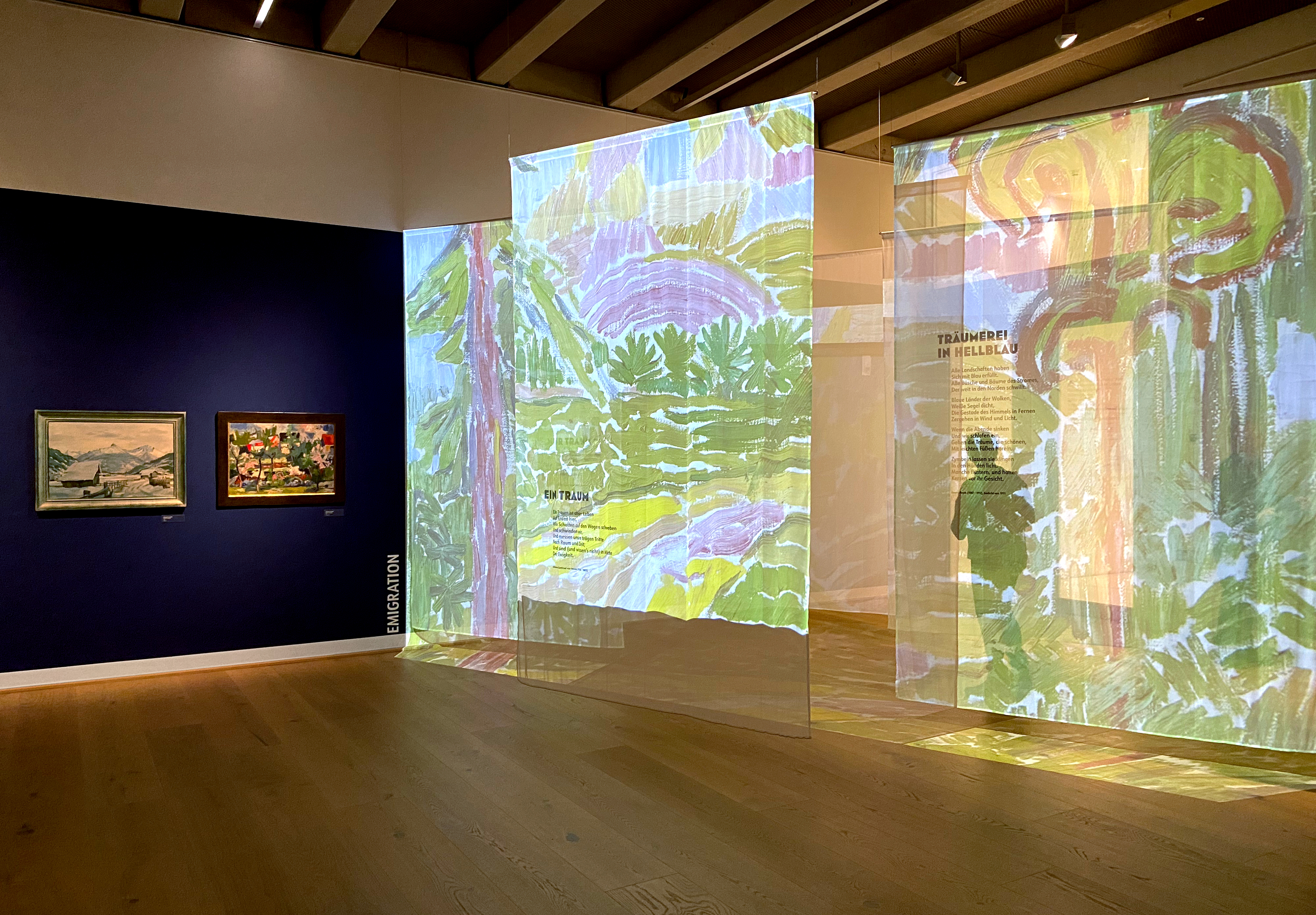 Links blaue Wand mit Bildern unter dem Stichwort "Emigration", rechts transparente Stoffbahnen mit Bildern und Texten