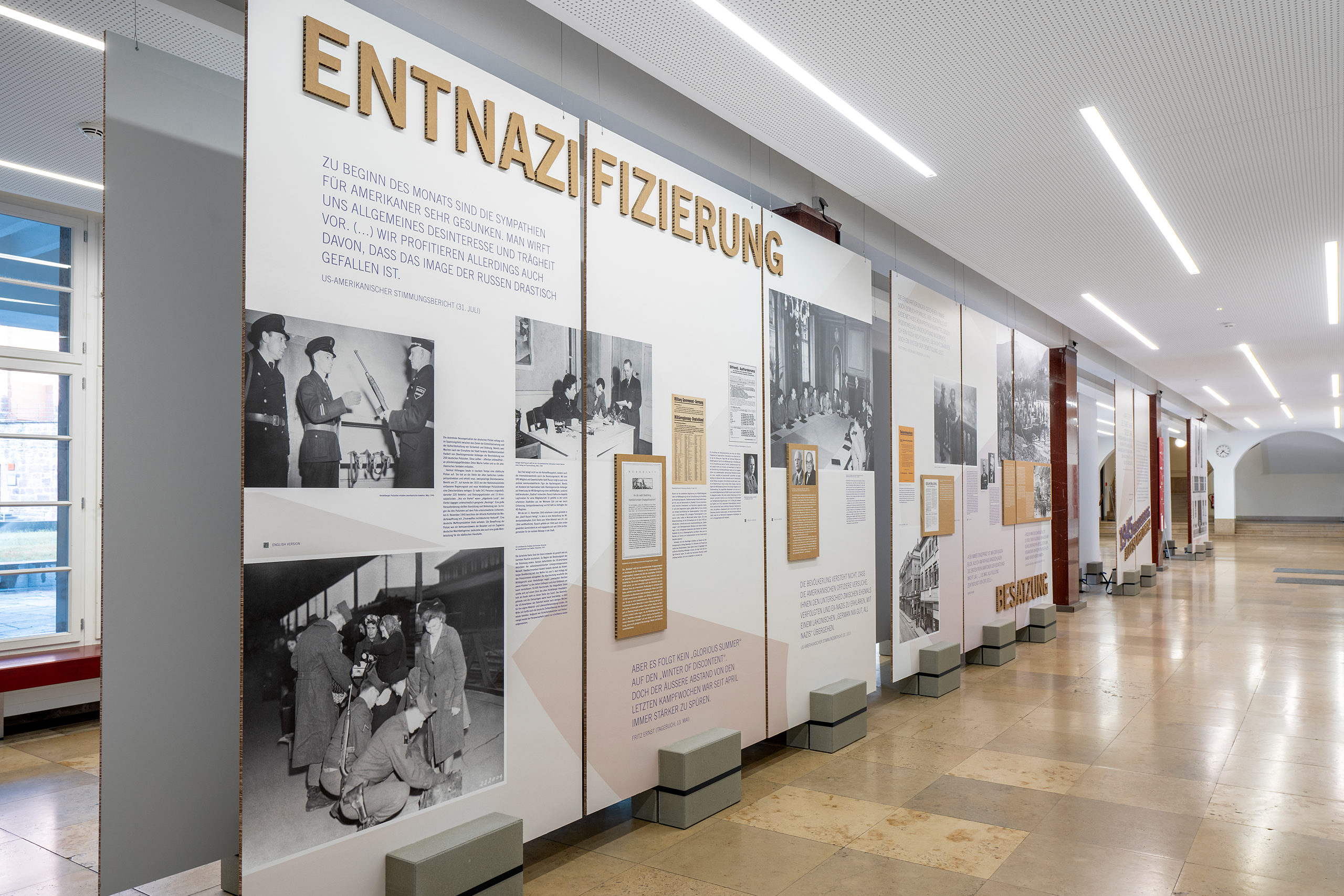 Ausstellungstafeln mit den Themen 'Entnazifizierung' und 'Besatzung', mehreren historischen schwarz-weißen Fotografien sowie erklärenden Texten